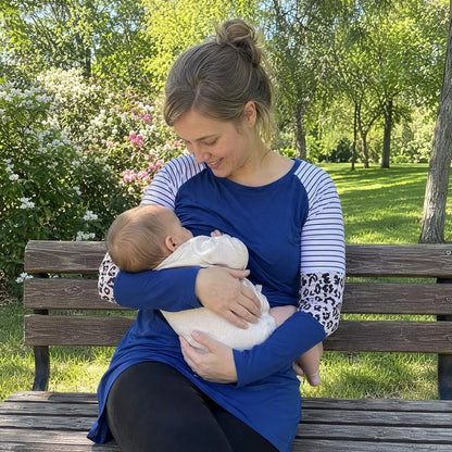 Femme assise dans un parc et portant un T shirt allaitement tout en allaitant son bébé 